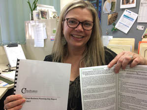 Picture of Liz Forsyth, Manager, holding two documents - The Business Planning Day Report written by Consultivation and Manjimup Home and Community Care new induction booklet.